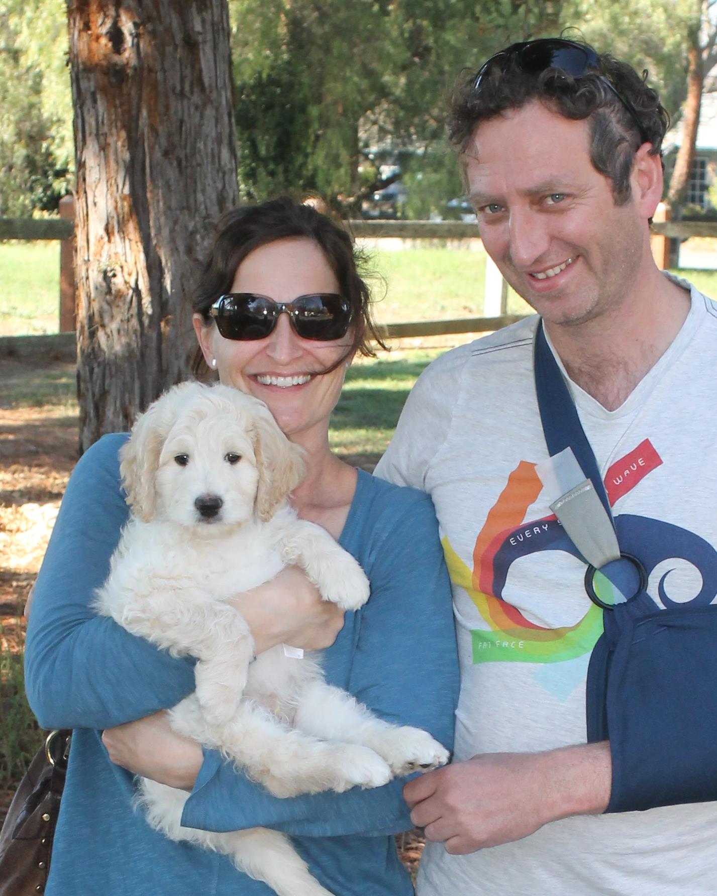 young couple outside holding new labradoodle puppy